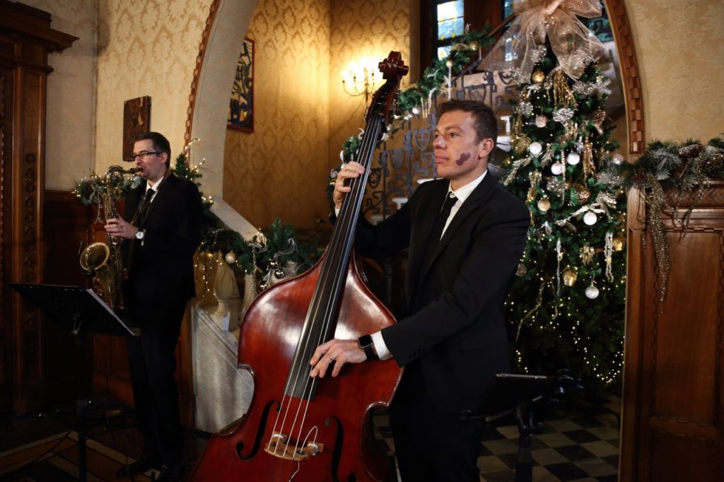 jazz bassist and saxophonist performing by a Christmas tree