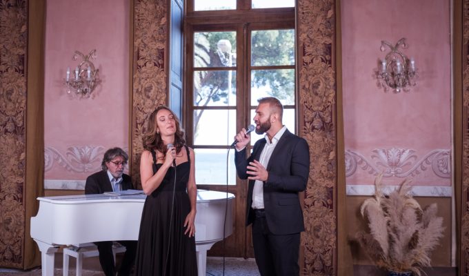 female and male singer performing with white piano