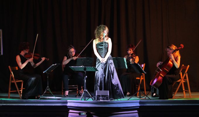 female singer and string quartet performing in a theater